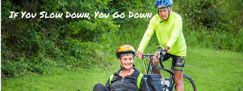 Tom Cawood pushing his wife in his bike, text "If you slow down, you go down"