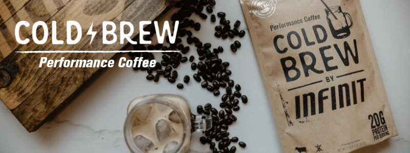 INFINIT Cold Brew in its bag, in a mug with ice, all on a table with coffee beans spread across