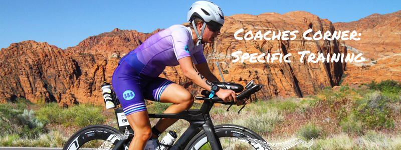 Woman Racing Bike through Red Rock Mountains, text "Coaches Corner: Specific Training"