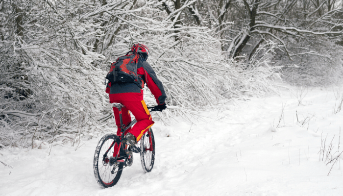 Man riding bike up snowy trail