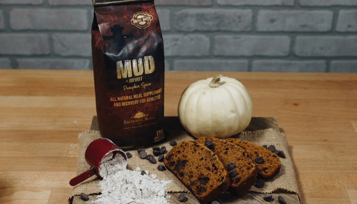 INFINIT Pumpkin Spice MUD next to small white pumpkiin ini front of protein bread