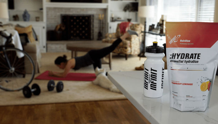 INFINIT Go Far and water bottle on table with woman doing yoga in background