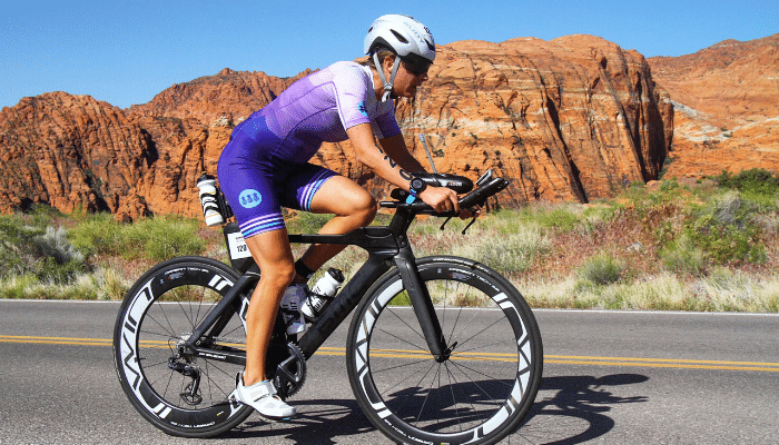 Kayla Bowker riding bike on road near red rock formation