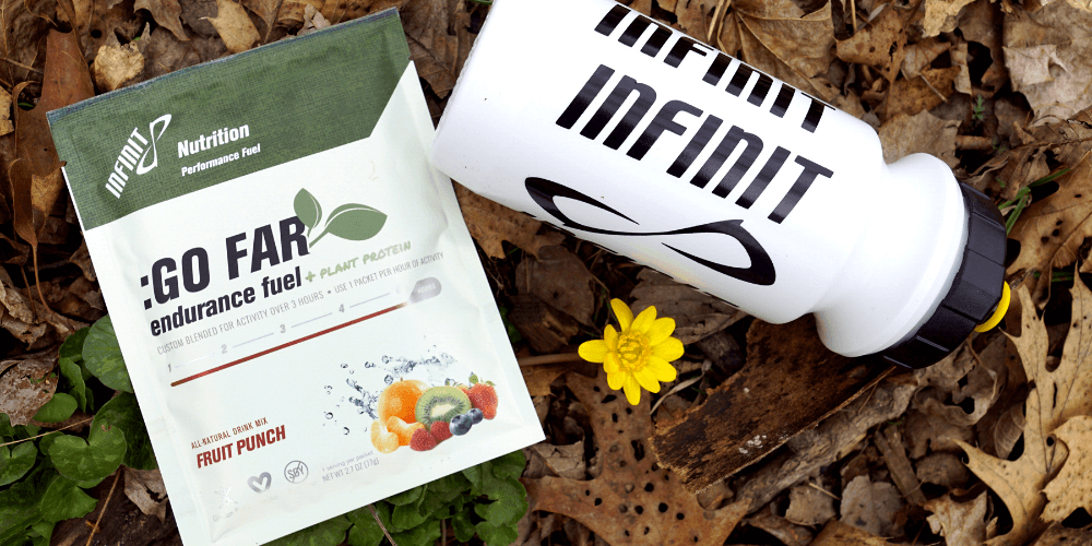 Bag of INFINIT: Go Far + Plant Protein sitting in leaves next to INFINIT bottle